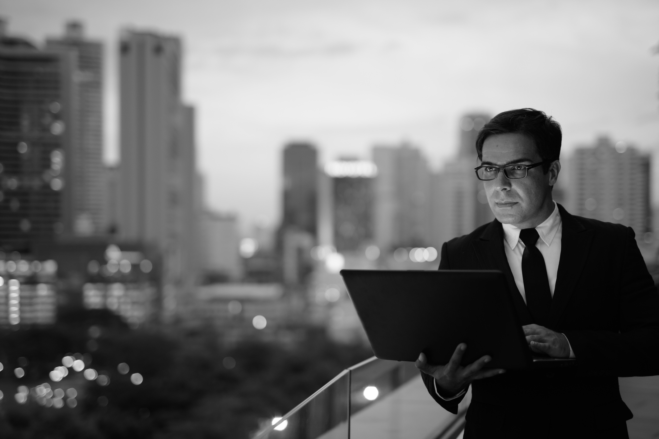 Portrait of handsome Persian businessman against view of the city in Bangkok Thailand in black and white horizontal shot