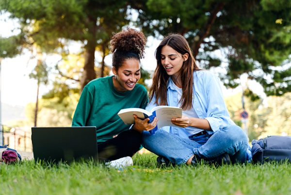 Two college students sitting at a park reading course material