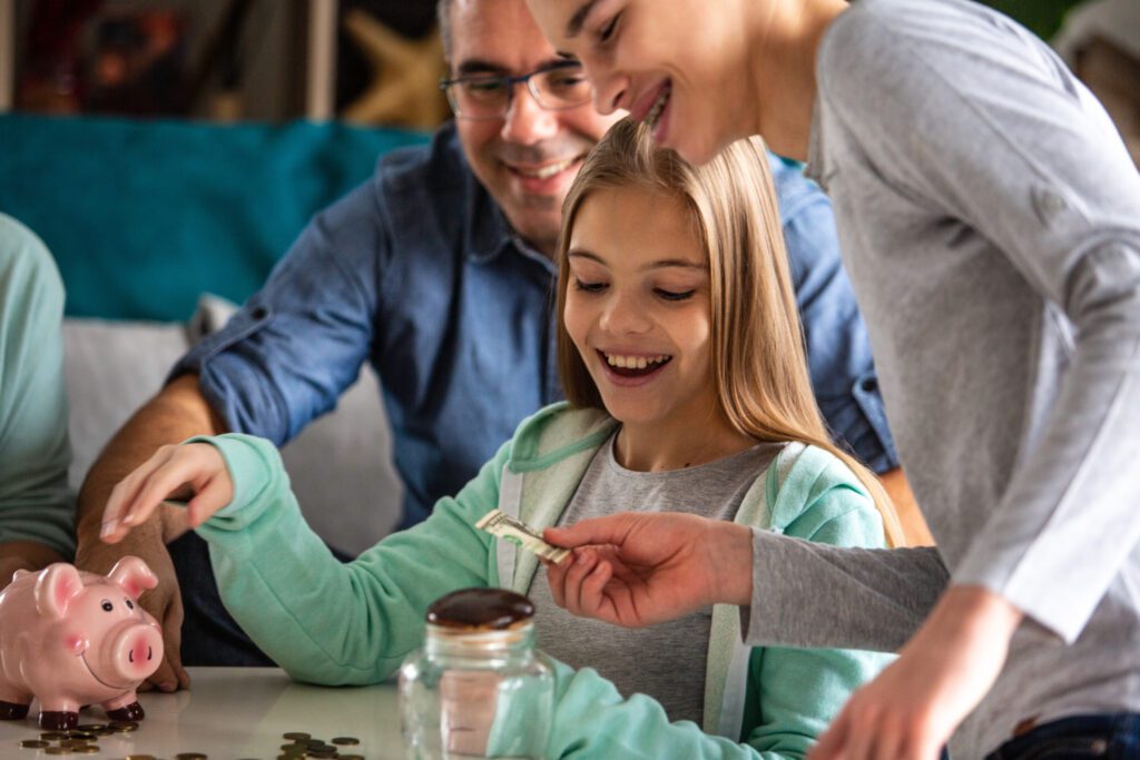 A girl is taking money from her brother to save it in a piggy bank.