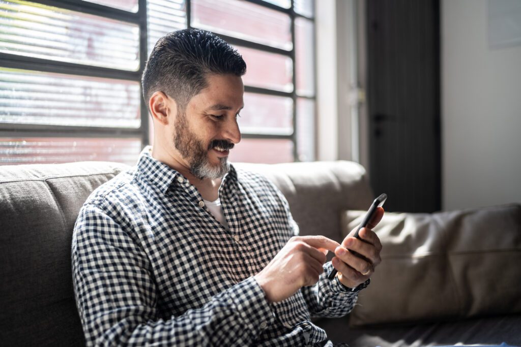 Mature man using smartphone on the couch at home