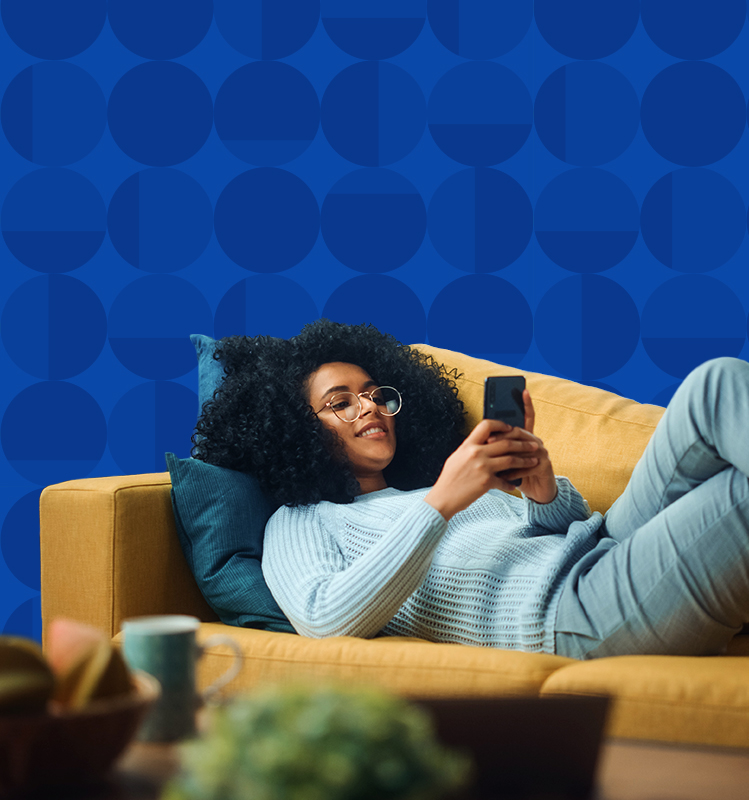 Woman laying on her couch while texting friends on her phone