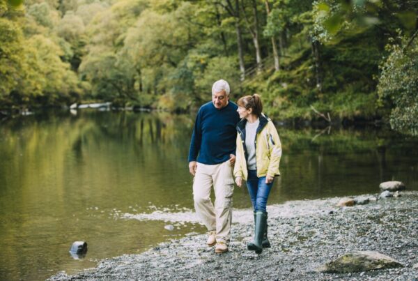 Elder couple hiking while walking next to the river talking