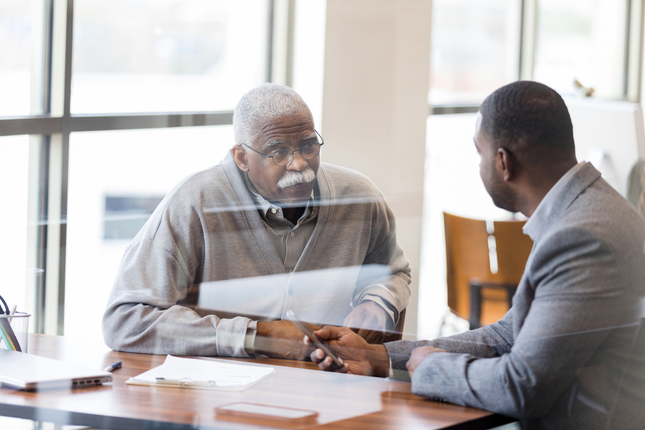 Senior man listens carefully as his financial advisor explains the bank's mobile app.