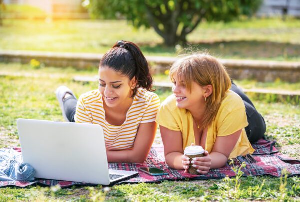 Two college students laying in the park on a picnic blanket after class