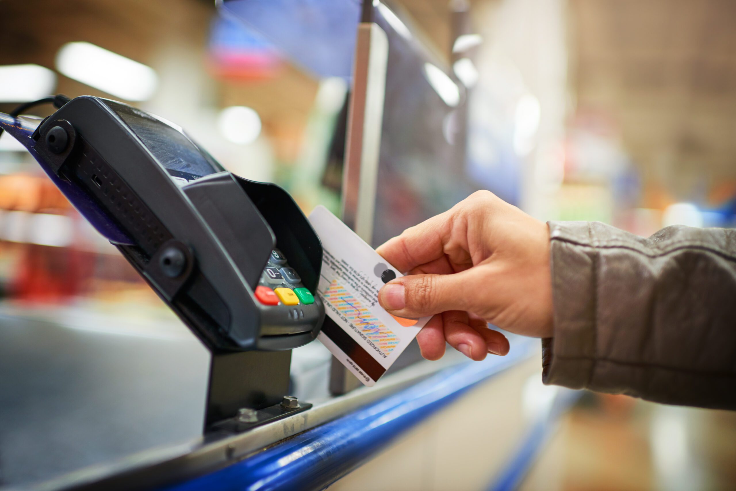 Cropped image of a person swiping their card on the card reader to make a payment