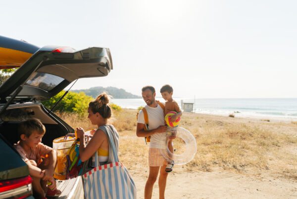 Happy family getting items out of their car after a road trip getting ready to have a fun time the beach