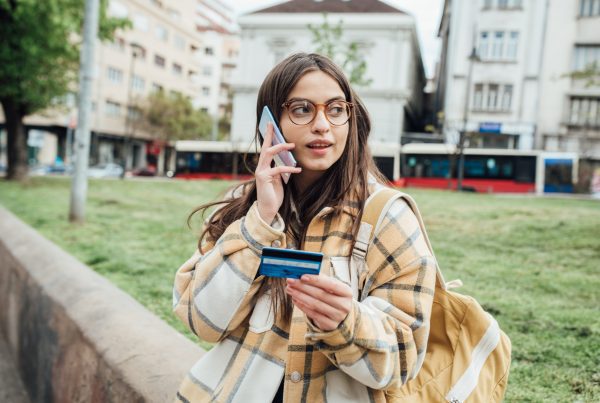 Woman calling on her phone with her credit card in hand.