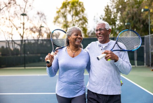 Old couple walking together in the tennis court after playing tennis together