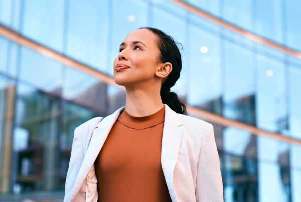 Confident businesswoman standing outdoors in front of a modern glass building, exuding professionalism and success.
