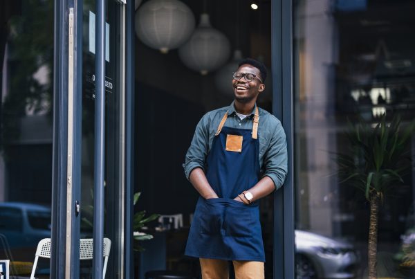 Cheerful café owner standing outside of his establishment.