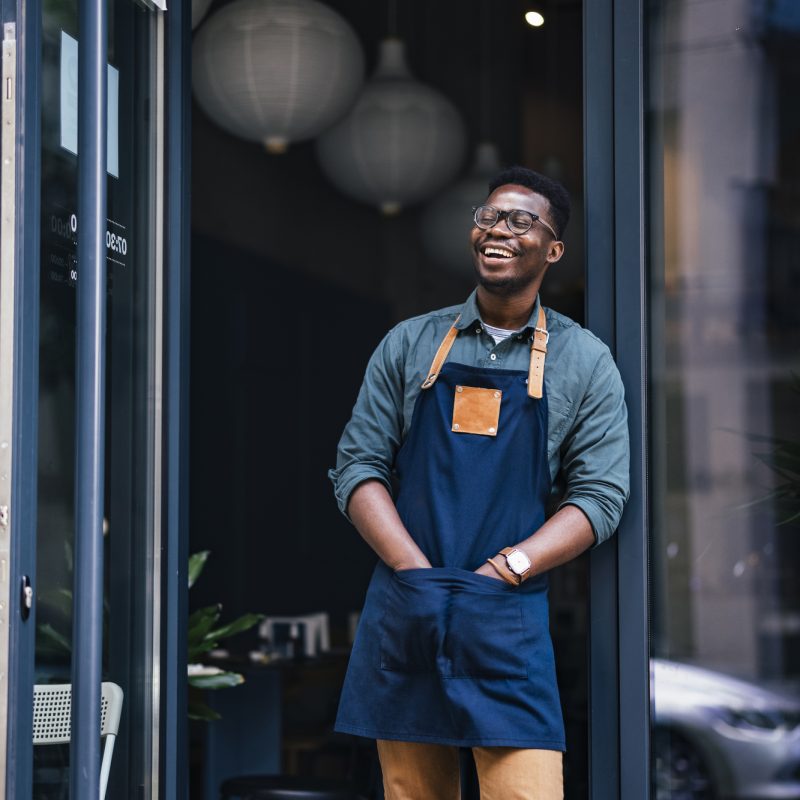 Cheerful café owner standing outside of his establishment.