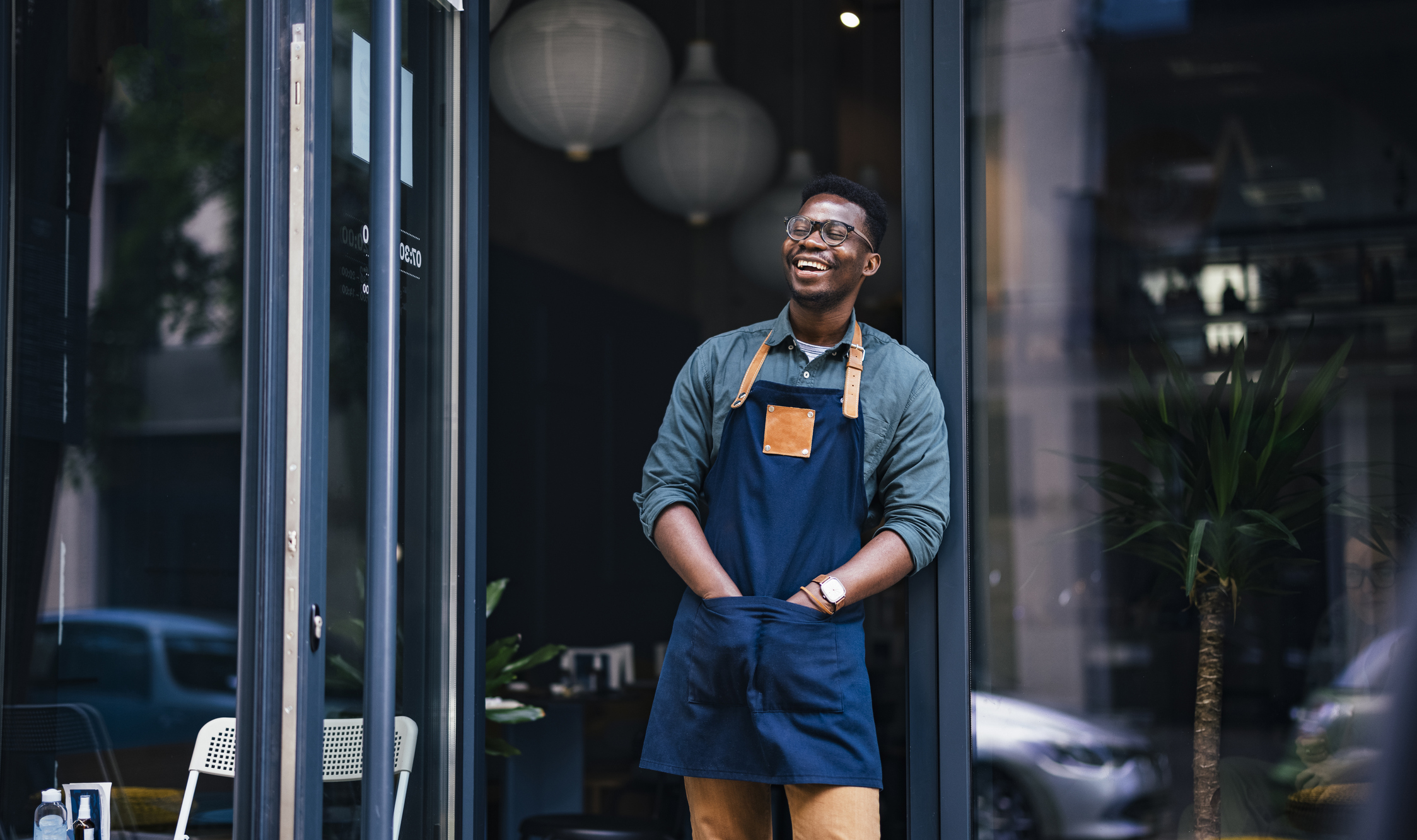 Cheerful café owner standing outside of his establishment.
