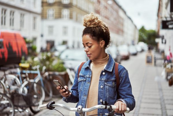 Woman stopped on the side of the road looking at her phone on her bike