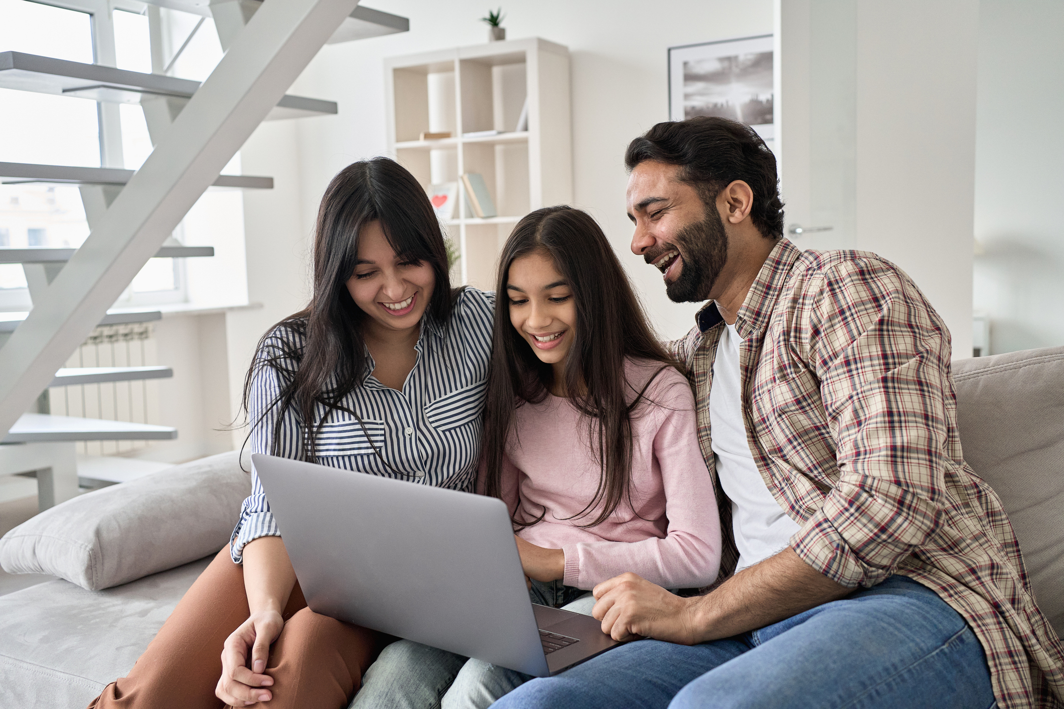Parents with child on laptop looking happy.