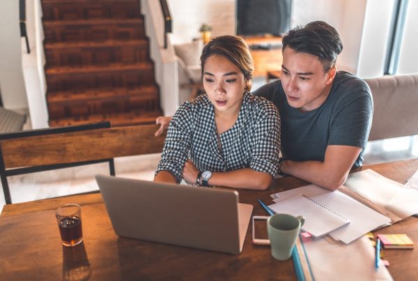 Serious young couple planning budget over laptop at table. Young man and woman calculating monthly expenses at home. They are in casuals.