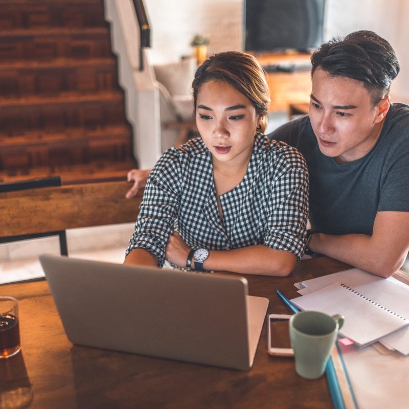 Serious young couple planning budget over laptop at table. Young man and woman calculating monthly expenses at home. They are in casuals.