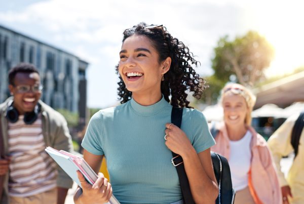 Walking, happy and girl with friends at university for learning, bonding and talking with fun. People, school and group of gen z students commuting outdoor ready for education at college campus.