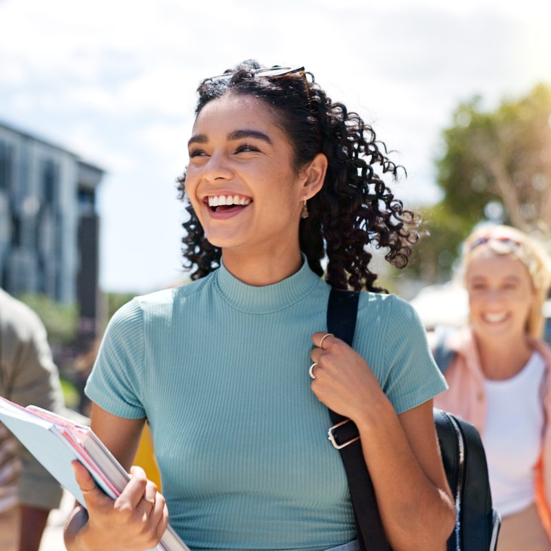 Walking, happy and girl with friends at university for learning, bonding and talking with fun. People, school and group of gen z students commuting outdoor ready for education at college campus.