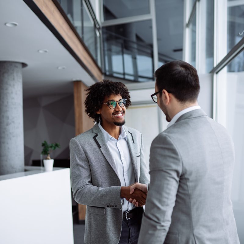 male employees shaking hands in hallway