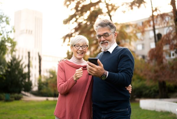 senior couple walking and using smart phone in public park