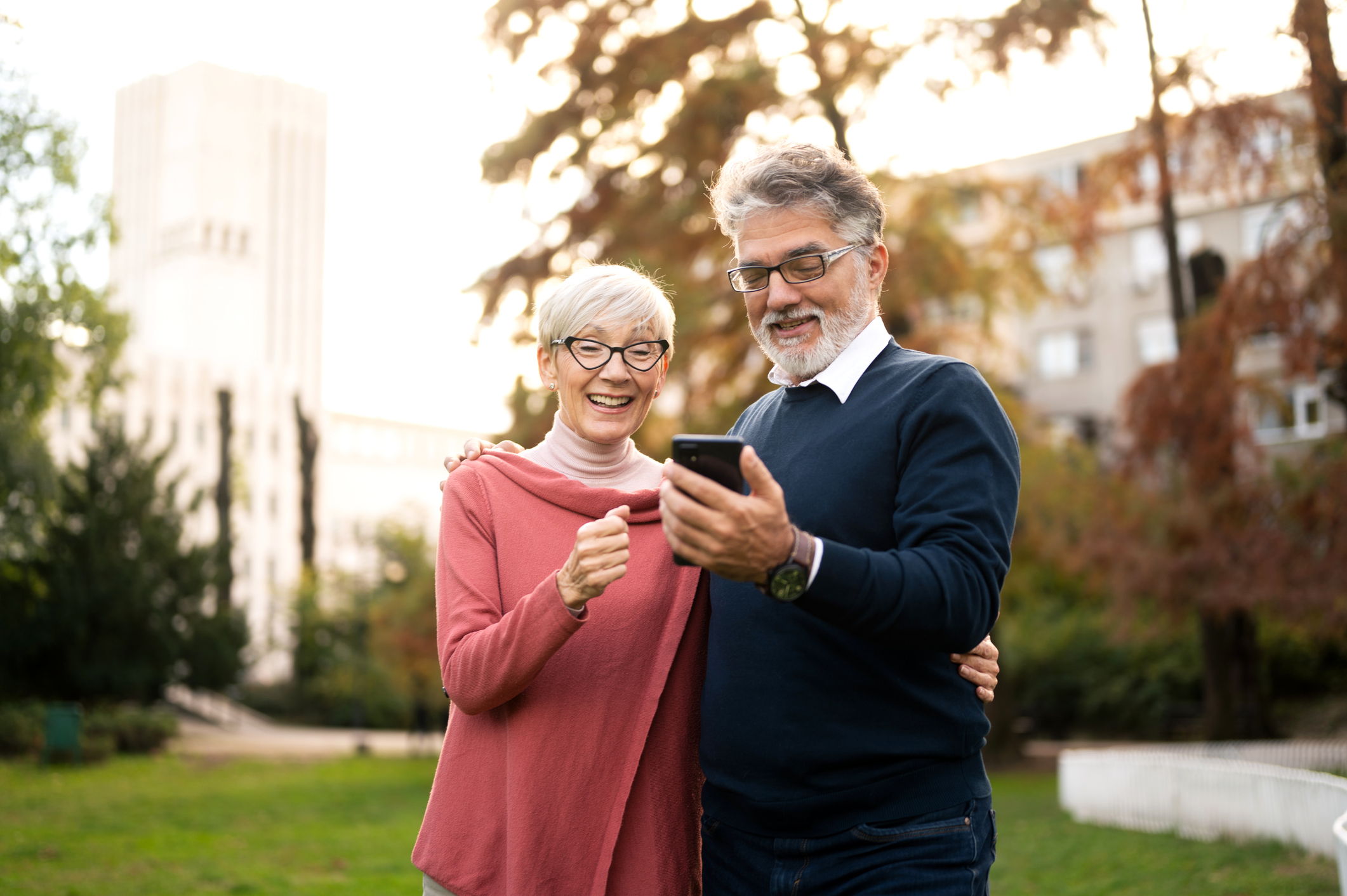 senior couple walking and using smart phone in public park