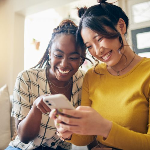 Young women, funny meme and smartphone, friends relax at home with social media and communication. Gen z, happiness and comedy online, chat and using phone with people on couch, mobile app and tech