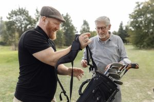 Senior retired man and his caddy playing golf in Europe