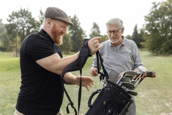 Senior retired man and his caddy playing golf in Europe