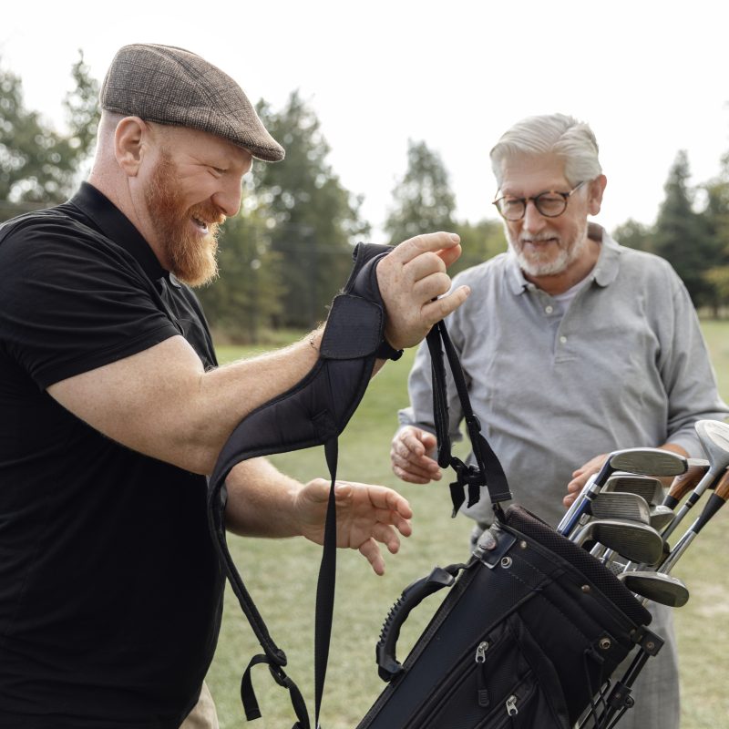Senior retired man and his caddy playing golf in Europe