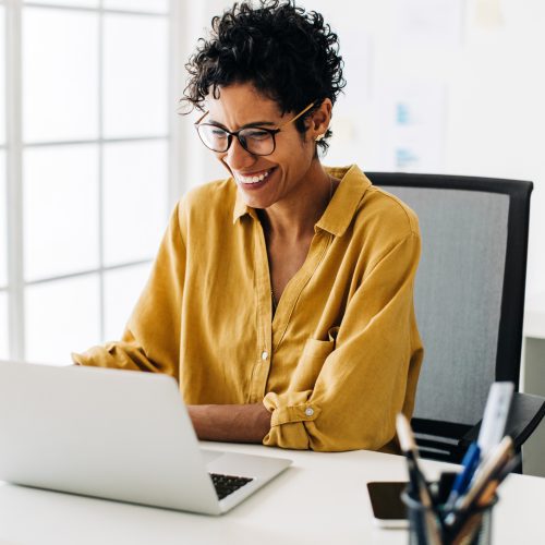 Graphic designer smiles as she works on a laptop in an office