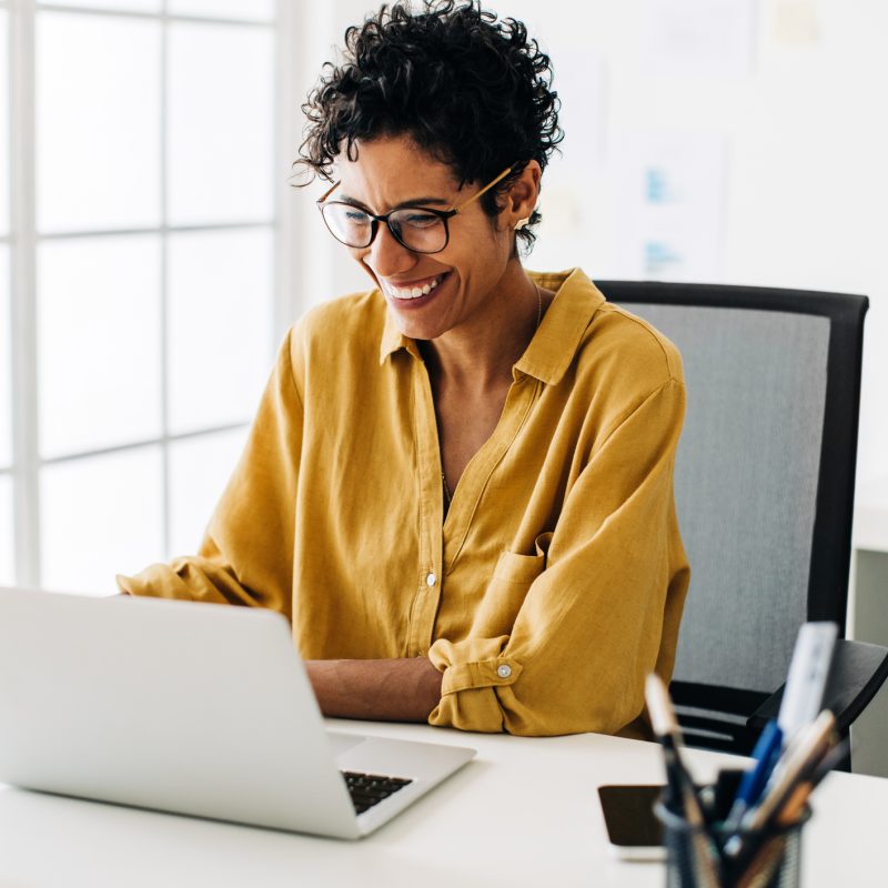 Graphic designer smiles as she works on a laptop in an office